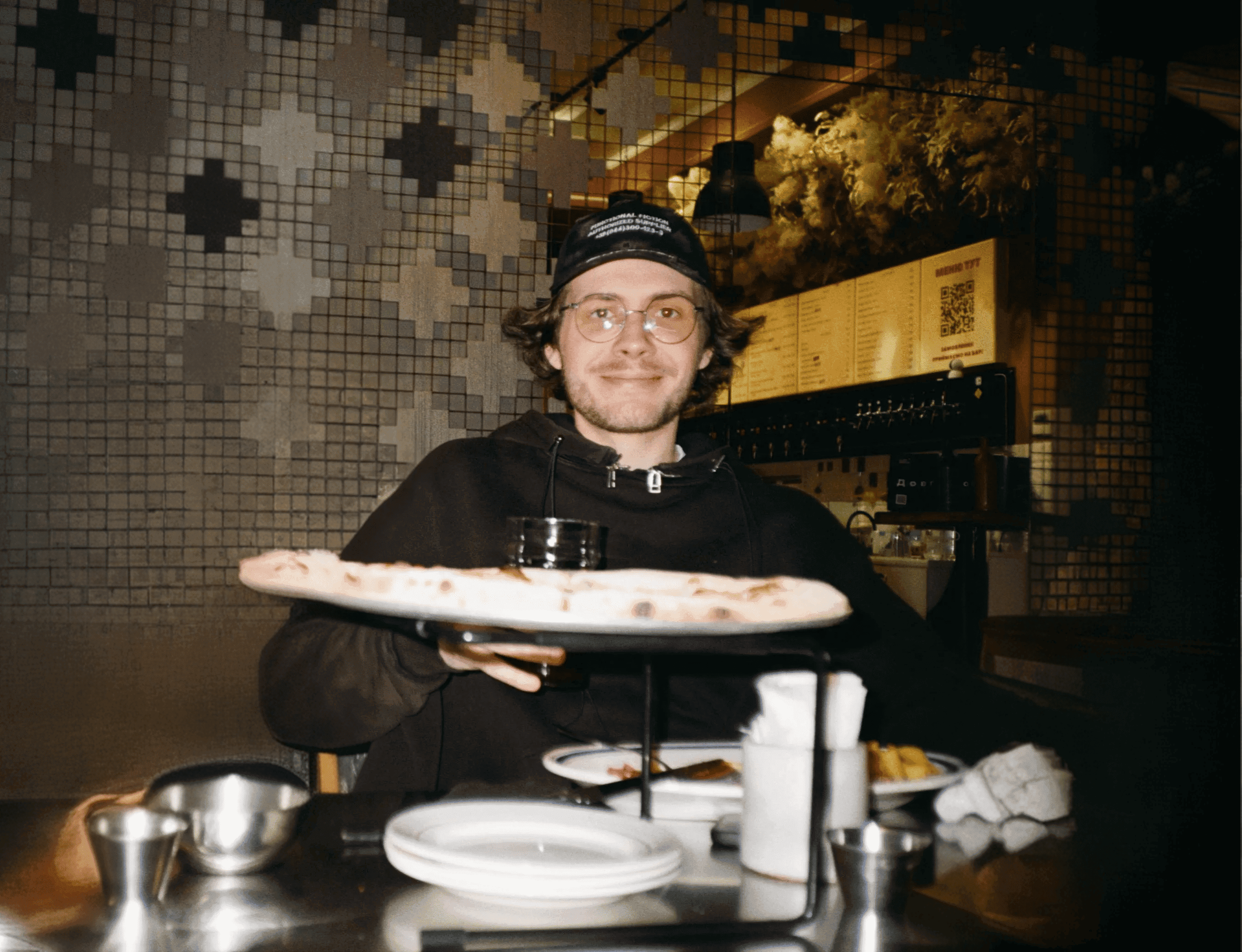 Danylo holding a pizza at a restaurant in Kyiv